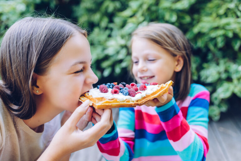 Kinder, die eine süße Waffel abbeißen.