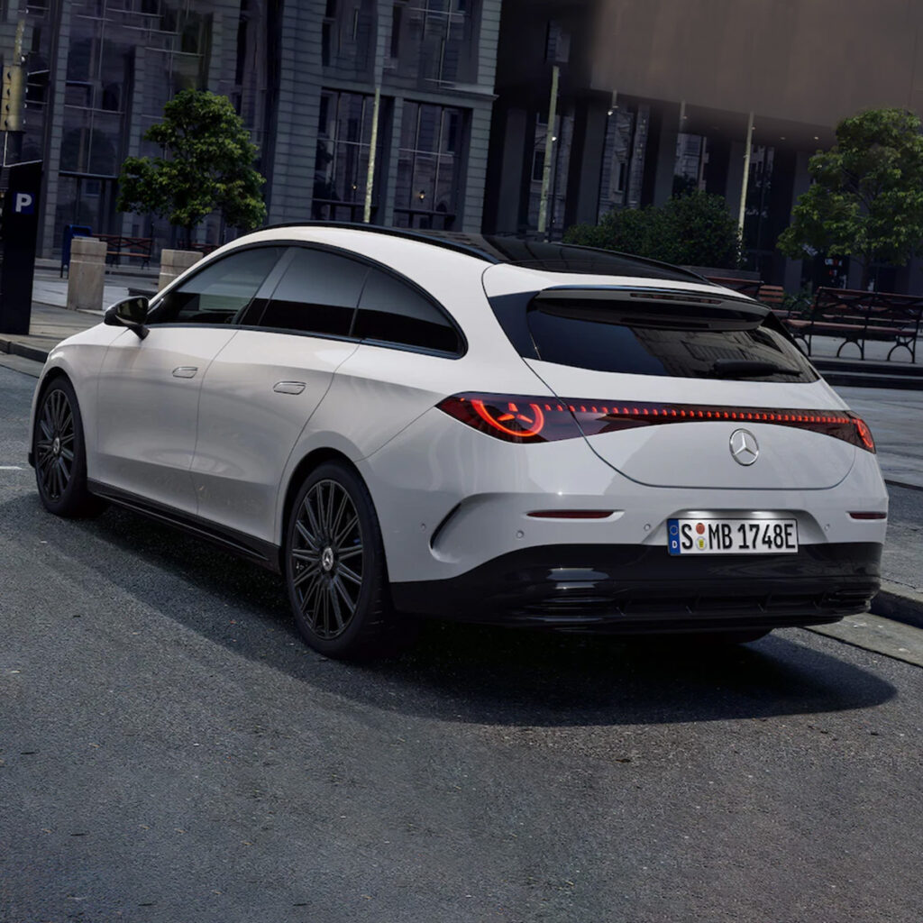 Heckansicht eines weißen Mercedes-Benz CLA Shooting Brake vor einem Gebäude auf einer Straße.