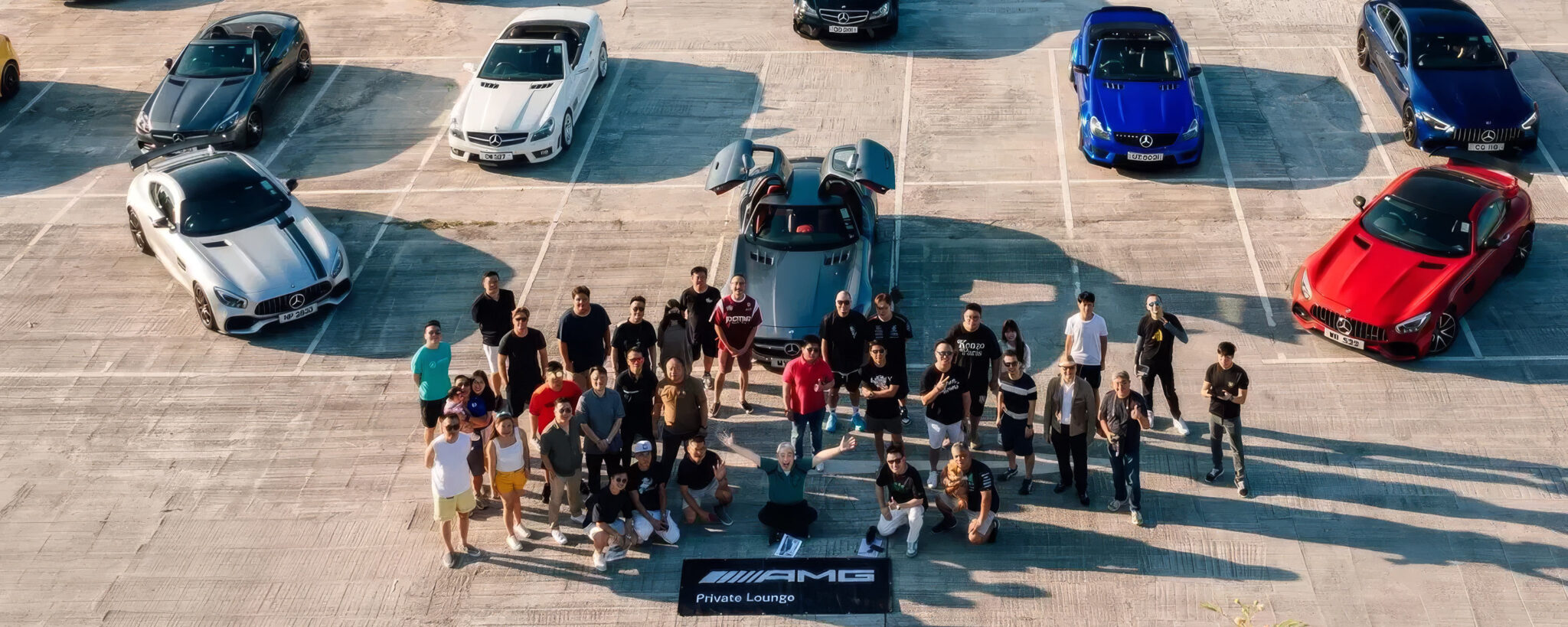 Drohnenaufnahme von Mitgliedern der AMG Private Lounge mit AMG Fahrzeugen im Hintergrund